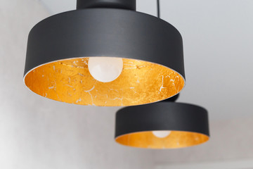 Two black metal pendant lights decorated inside by golden foil