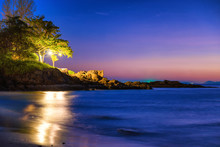 Night View Of Sand Beach, Sea And Rocky Shore With Trees At Tropical Island