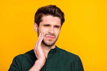 Ouch. Close up photo of upset sad guy feel ill suffer from disease toothache touch his cheek face cry need medical dentistry treatment wear casual style clothing isolated over yellow color background