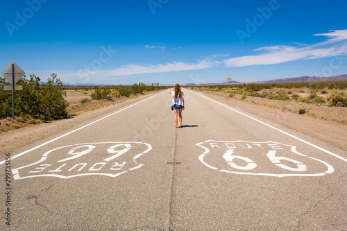 Young woman standing on the Route 66 road in Californian desert Wallpaper Mural