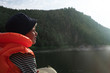 © ILIA - Little boy in a life jacket floats on a boat on the river and looks at the rising sun
