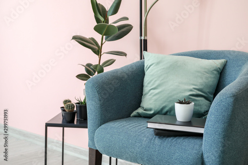 Stylish armchair and table with houseplants in room