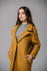 elegant pretty woman posing in beige coat, isolated on grey