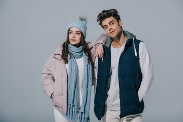 stylish young couple posing in winter outfit, isolated on grey