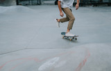 Young boy performing tricks with the skateboard in a skate park