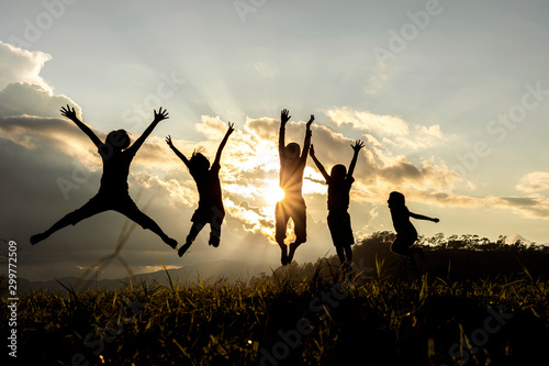 Cuadros en Lienzo Silhouette group of happy children jumping playing on mountain at sunset, summer