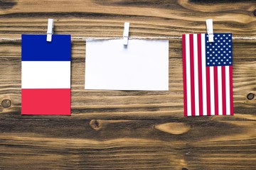 Wall Mural - Hanging flags of France and United States attached to rope with clothes pins with copy space on white note paper on wooden background.Diplomatic relations between countries.
