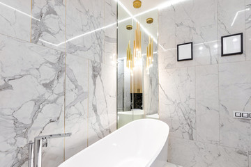 Luxury designer marble-tiled bathroom with gilded details for a cozy evening of body care and relax