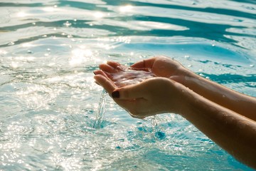 Woman hands in water inviting you over sunset golden rays