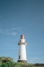 White And Orange Lighthouse Under Blue And White Skies