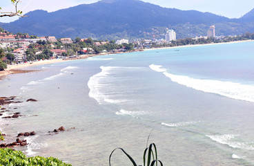 Wall Mural - sea waves roll on the sandy shore, foam and spray of water, against the backdrop of mountains and blue sky in the style of bounty