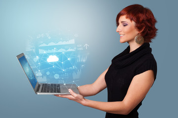 Wall Mural - Woman holding laptop projecting cloud based system symbols and informations