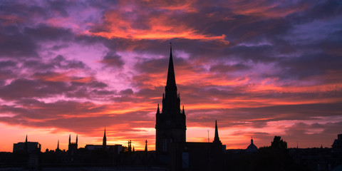 Silhouette of cityscape of Aberdeen in Scotland. Church tower and buildings in the city center. Beautiful  colorful sunset in Aberdeen. Pink and blue sky. Low light photography.