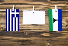 Hanging Flags Of Greece And Lesotho Attached To Rope With Clothes Pins With Copy Space On White Note Paper On Wooden Background.Diplomatic Relations Between Countries.