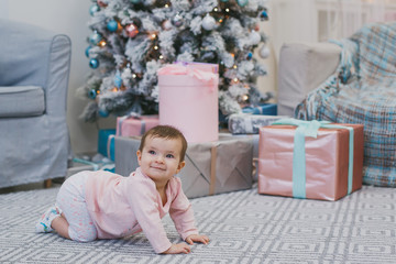 little girl child of 6 months crawls near a New Year tree 