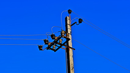 The pillar is electric. Electric wires. Power lines. Crows on wires