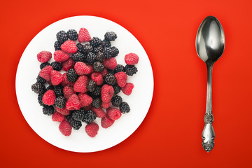  blackberry and raspberry on a white plate. blackberry and raspberries on a background top view. Vegetarian food.