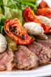 © Alexander - Roast beef salad with sun-dried tomatoes. Arugula, tomato and cucumber on white plate, macro view