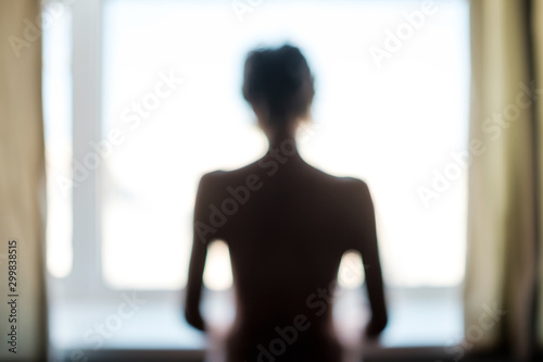 Cuadros en Lienzo Unknown female person standing near window alone.