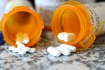 Precription bottles of pain pills on a granite countertop. 