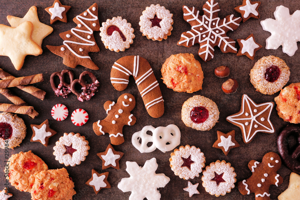 Variety of Christmas cookies and sweets. Top view over a dark stone background. Holiday baking concept. - obrazy, fototapety, plakaty 