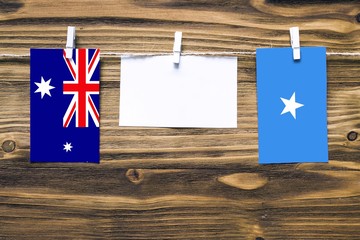 Canvas Print - Hanging flags of Heard and Mcdonald Islands and Somalia attached to rope with clothes pins with copy space on white note paper on wooden background.Diplomatic relations between countries.