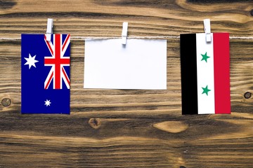 Canvas Print - Hanging flags of Heard and Mcdonald Islands and Syria attached to rope with clothes pins with copy space on white note paper on wooden background.Diplomatic relations between countries.