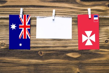 Poster - Hanging flags of Heard and Mcdonald Islands and Wallis And Futuna attached to rope with clothes pins with copy space on white note paper on wooden background.Diplomatic relations between countries.