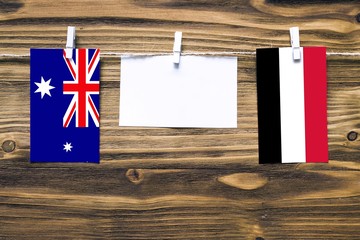 Poster - Hanging flags of Heard and Mcdonald Islands and Yemen attached to rope with clothes pins with copy space on white note paper on wooden background.Diplomatic relations between countries.