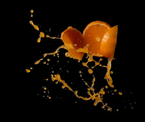 Sticker - Orange juice with orange fruit slices splash or explosion flying in the air isolated on black background