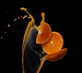 Wall Mural - orange juice with orange fruit slices splash or explosion flying in the air isolated on black backgr