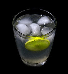 lemonade with ice in crystal glass on black background