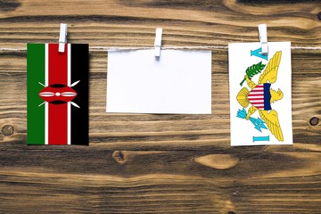 Hanging flags of Kenya and United States Virgin Islands attached to rope with clothes pins with copy space on white note paper on wooden background.Diplomatic relations between countries.