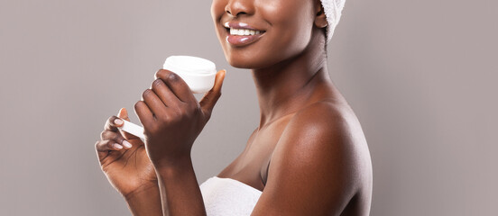 Wall Mural - Black woman holding open jar of face cream in hands