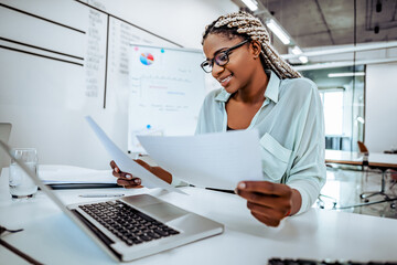 Smiling business woman reads documents, works in a bright office.