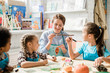 © pressmaster - Happy young teacher showing group of schoolkids halloween pumpkin decoration
