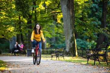 Wall Mural - Urban biking - woman riding bike in city park