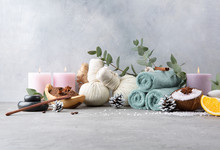 Beautiful Winter Spa Relax Concept. Coffee With Cinnamon Scrub, Cotton Pouches With Herbs For Massage, Sea Stones, Eucalyptus And Other Spa Accessories On Grey Table.