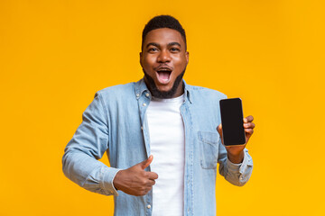 Poster - Surprised african man holding smartphone and showing thumb up