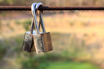 a couple of padlocks fixed to cable of the bridge at tourist attraction, symbolic of together and fo