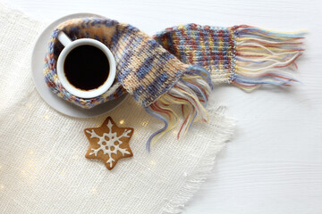 Wall Mural - cup with scarf espresso and snowflake gingerbread cookie on the table top view. black coffee in winter style