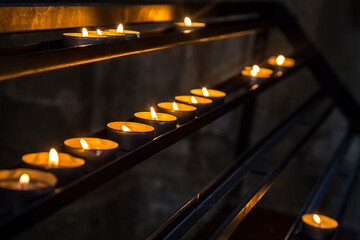  Prayer burning candles in a church on a dark background. Religious concept.