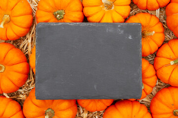 chalkboard sign on pumpkins and a straw hay background