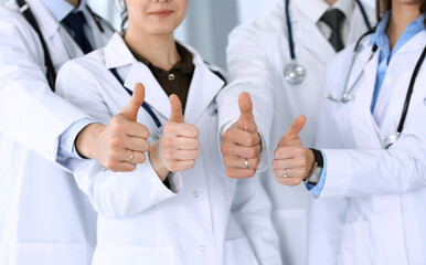 Group of modern doctors standing as a team with thumbs up in hospital office. Physicians ready to examine and help patients. Medical help, insurance in health care, best desease treatment and medicine