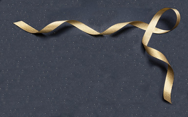 Wall Mural - golden satin ribbon on black background, copy space