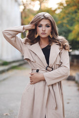 Wall Mural - beautiful girl with dark hair in elegant clothes posing in autumn street