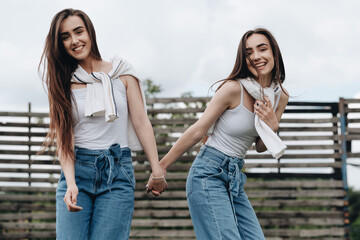 Portrait of Two Young Brunette Twins Sisters Dressed Alike in Jeans and White T-shirt, Best Friends Forever Concept