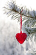 Read heart hanging on a snow-covered pine tree, vintage glass Christmas decoration