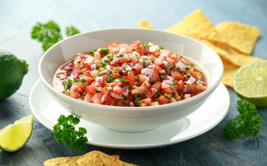 Wall Mural - Mexican Tomato Salsa in white bowl with lime, red onion, jalapeno pepper, parsley and tortilla chips