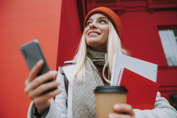 Wall Mural - Pretty lady with modern smartphone standing near university